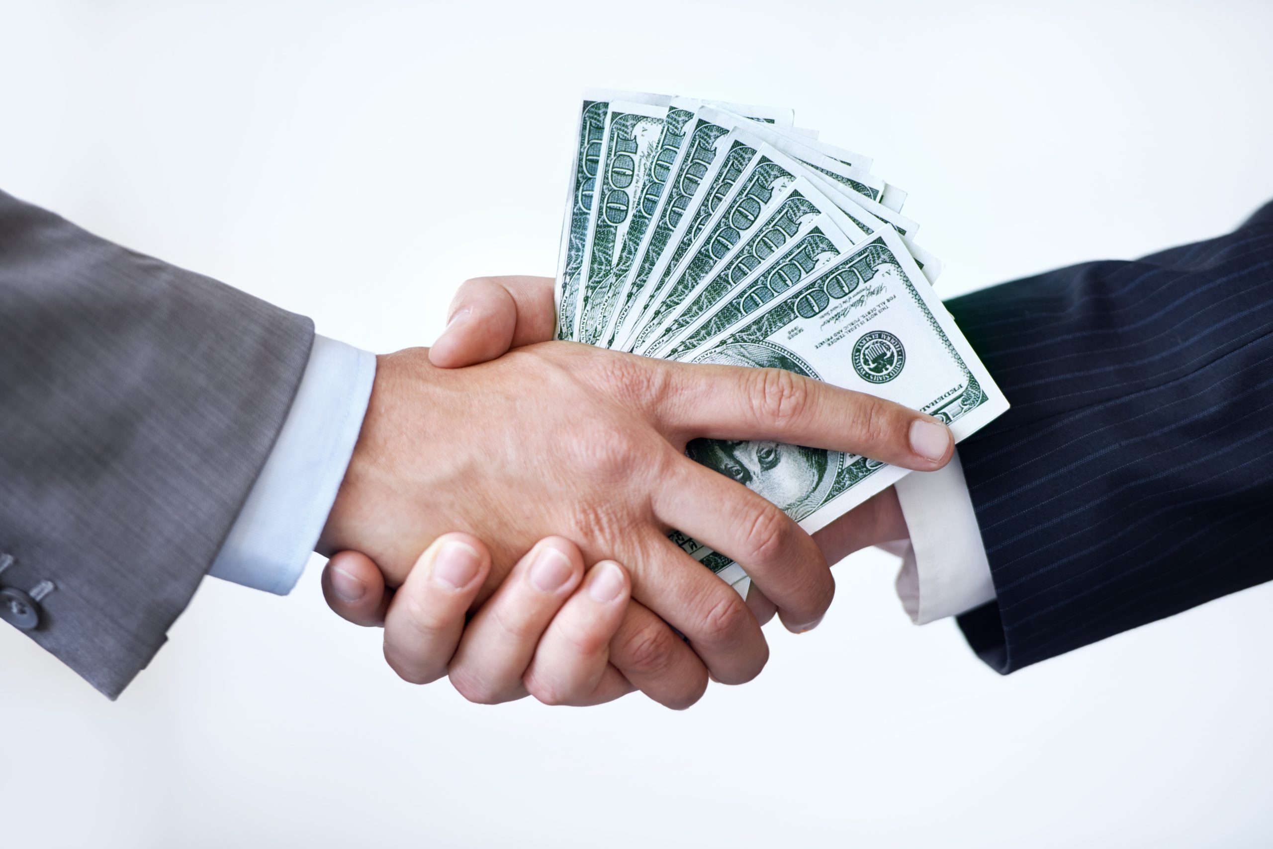 Studio shot of two men shaking hands after making a monetary deal
